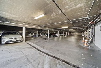 A parking garage with a car parked and a few orange cones.
